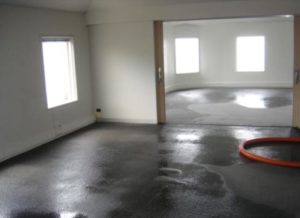 Basement with wet floors receiving a waterproofing service.