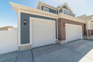 Front view of home garage with two white doors and brick and wood exterior wall
