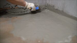 Worker waterproofing a wall with a cement-polymer waterproofing membrane 